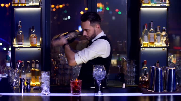 Barman mixing cocktail ingredients using shaker