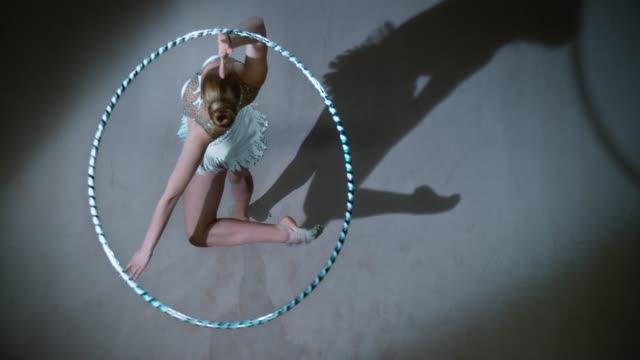 SLO MO LD Above a rhythmic gymnast pivoting while rotating a hoop above her head