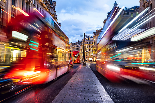 London typical red bus blurred motion at night in Oxford Circus