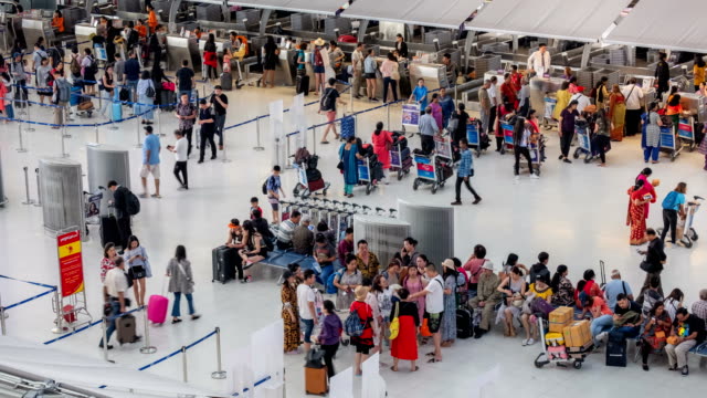 4K Time lapse of Crowded passenger waiting in line at airport check-in counter in airport terminal with baggage