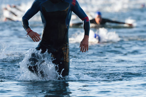 triatleti che escono dall'acqua sul triathlon - competitive sport competition swimming wetsuit foto e immagini stock