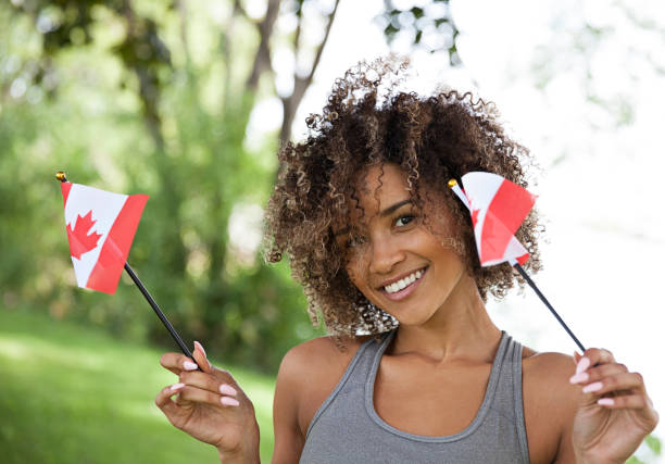 Young Proud Canadian Woman Happy young woman with Canadian flag outdoor portrait victoria day canada photos stock pictures, royalty-free photos & images