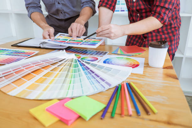 istock Teamwork of young creative designers working on project together and choose color swatch samples for selection coloring on digital graphic tablet at workspace 1139733278
