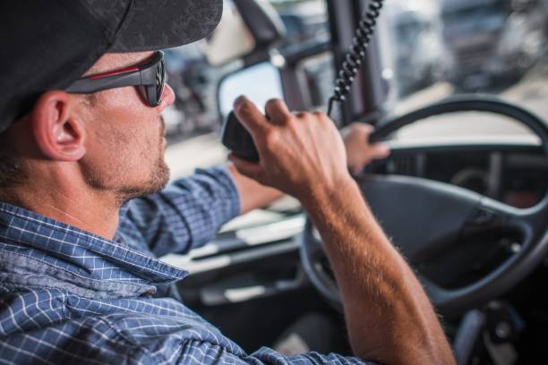 Truck Driver CB Talking Caucasian Truck Driver in his 30s CB Talking with Other Drivers in the Convoy. Heavy Load Transportation Communication. walkie talkie photos stock pictures, royalty-free photos & images