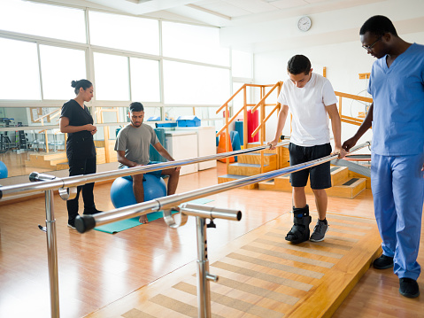 Young men exercising in the physical therapy room next to their health care providers.
