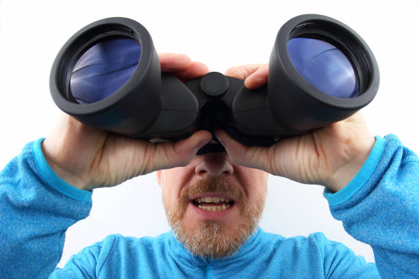 istock bearded man in a blue jacket looking through binoculars on a light background 1139747775