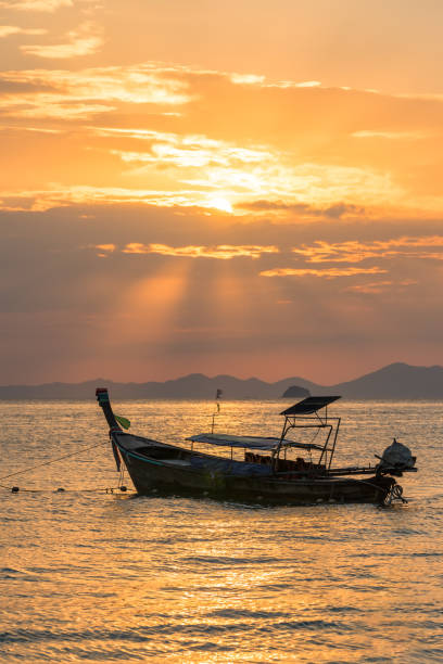 istock Golden sun rays and local empty thai long-tail boat under them in sea water 1139747921