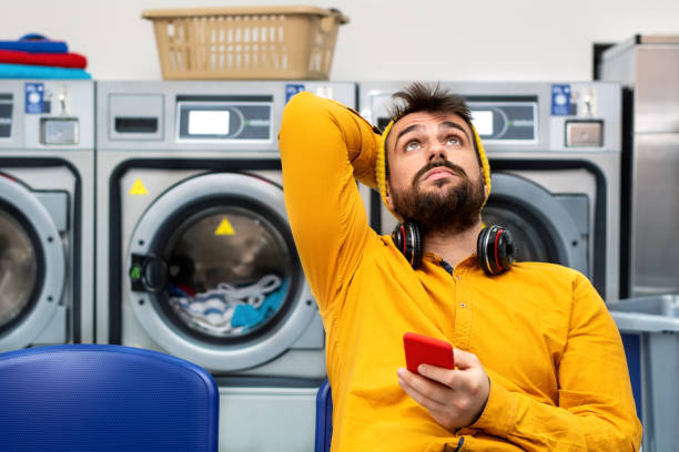 el hombre joven lavando su ropa - all laundry detergent audio fotografías e imágenes de stock