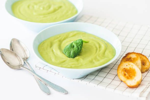 Broccoli cream soup in pastel blue plate on white background. Healthy food concept