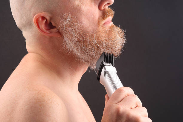 istock Bearded man with trimmer to adjust beard in hand 1139756179