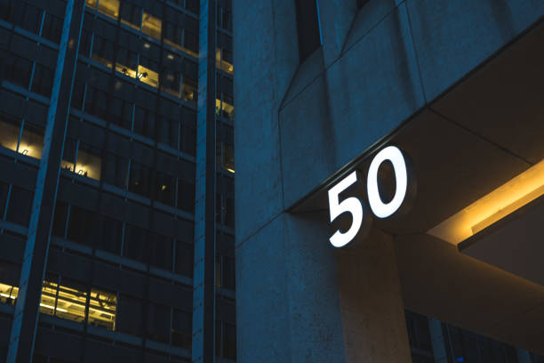Close up of a building facade showcasing a blue number thirteen sign, highlighting urban architecture and textured stonework