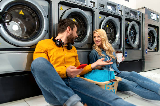 jeune couple gai faisant la lessive ensemble à la boutique de laverie automatique. - all laundry detergent audio photos et images de collection