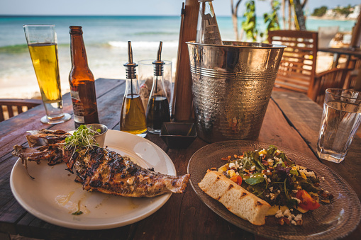 Caribbean, Grilled fish and salad lunch layed out on a beachside table