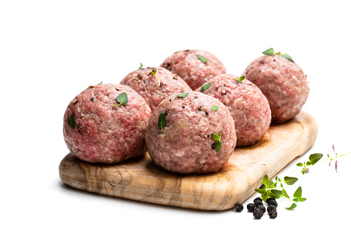 Raw meat  balls on wooden cutting board isolated on white