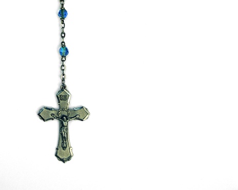 color image of a rosary crucifix against a white backdrop