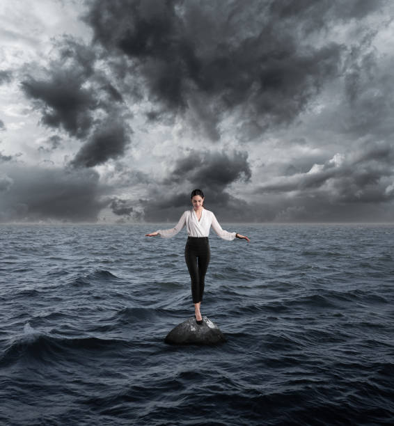 imprenditrice che bilancia sulla pietra - storm sea business uncertainty foto e immagini stock