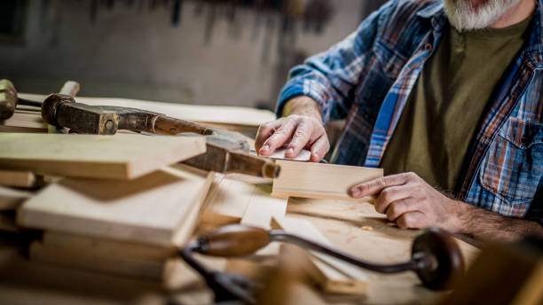 istock Senior woodworker using a sandpaper on a piece of wood 1139780404