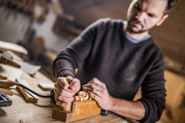 istock Carpenter working on a piece of wood with a hand plane 1139780411