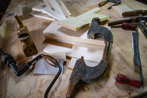 Close-up of rustic woodworking tools on a table in a carpentry workshop.