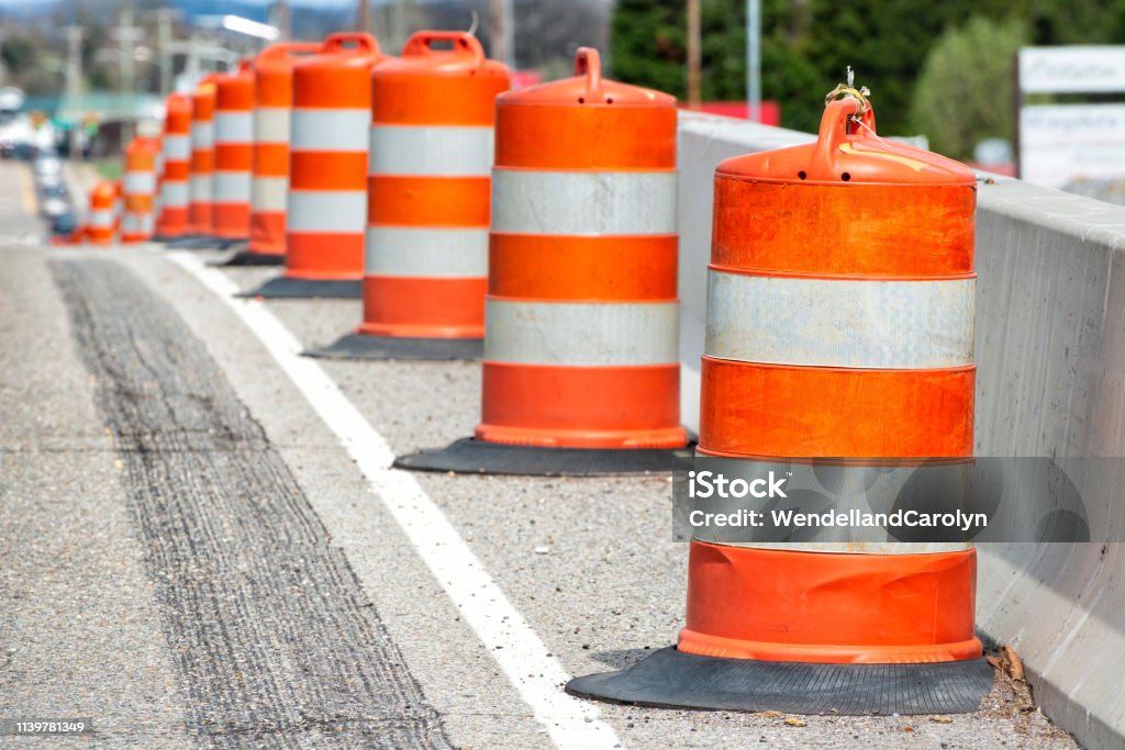 Traffic Barrels With Shallow Depth of Field Horizontal close-up shot of orange and white striped traffic barrels down the side of a road with shallow depth of field. Road Construction Stock Photo