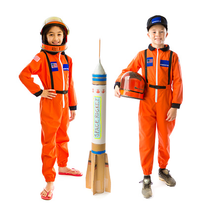 Portrait of a two young child, a boy and a girl with career aspiration of being a space astronaut on white background. They are wearing a astronaut suit costume, looking at camera