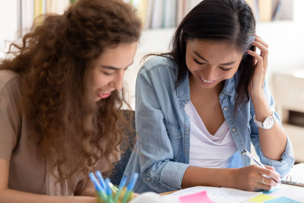 dwie szczęśliwe zróżnicowane dziewczyny kolegów z college'u studiujących razem w kampusie - teacher preparation two people teamwork zdjęcia i obrazy z banku zdjęć