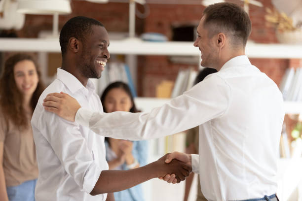 Caucasian executive handshaking promoting successful happy african worker expressing gratitude Caucasian executive boss handshaking promoting successful happy african black worker expressing gratitude praising shaking hand appreciating for good work, reward recognition acknowledgement concept encouragement stock pictures, royalty-free photos & images