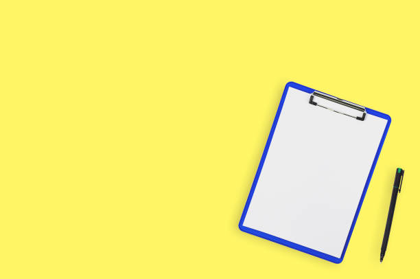 istock One blue plastic clipboard with glossy chrome clamp and white blank paper sheets near black pen on yellow office table. Top view. Business, education or medical concept. Copy space 1139792267