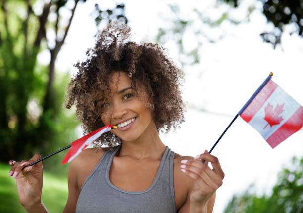 Young Proud Canadian Woman Happy young woman with Canadian flag outdoor portrait victoria day canada photos stock pictures, royalty-free photos & images