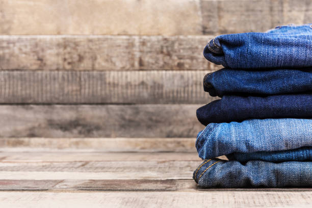 Stack of folded blue jeans on old wood background