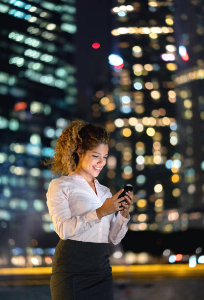 istock Business woman texting on her mobile phone at night 1139805761