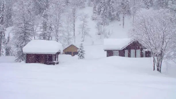 Snowfall in skitouring lodge in Siberia. Houses covered with snow