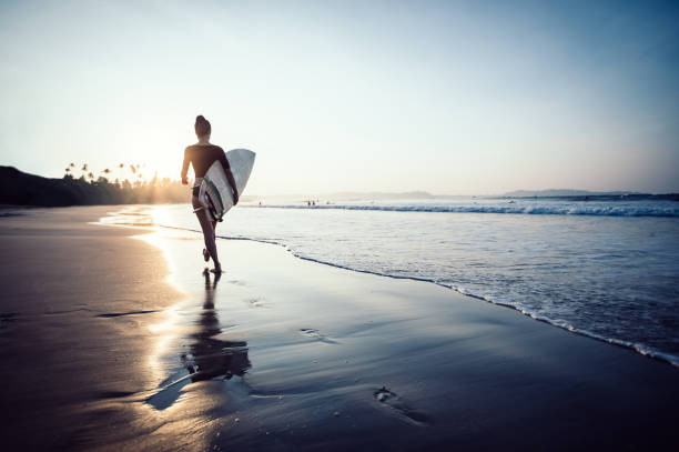 istock Surfer woman walking with surfboard on sunrise beach 1139814981