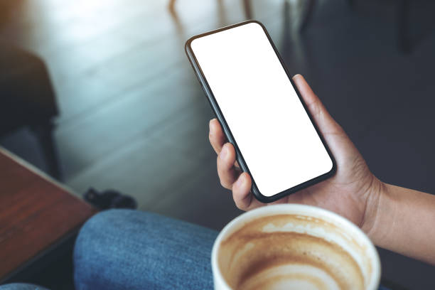 istock Mockup image of a hand holding black mobile phone with blank screen while drinking coffee in cafe 1139821359