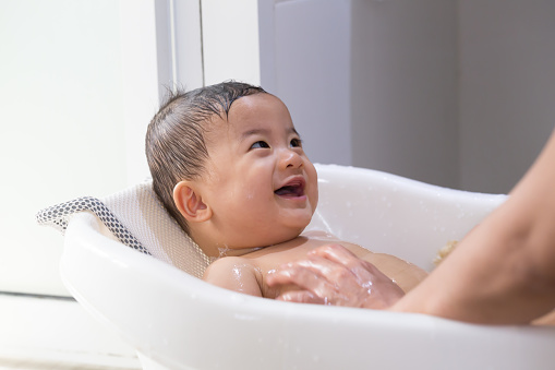 Asian baby boy taking a bath by mom. Hygiene and care for young children concept