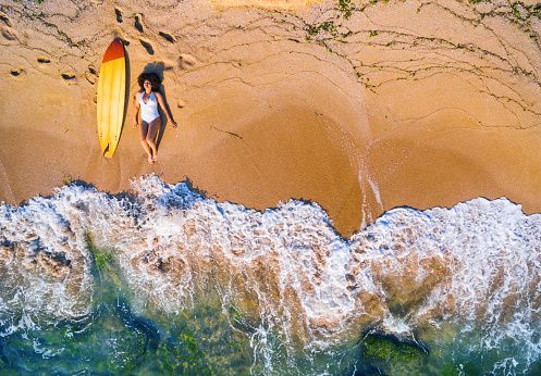 Aerial view of a surfer girl resting on a beach.