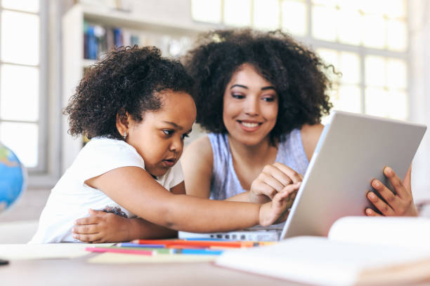 mujer joven y un niño apuntando a la laptop - child digital tablet mother teaching fotografías e imágenes de stock