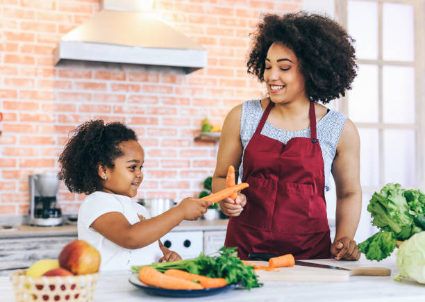 istock Mother and daughter playing with carrots 1139828535