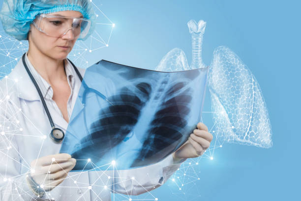 A doctor examining a lungs image for treatment and diagnosis. A closeup of young doctor in glasses and with stethoscope examining the ribbons image with large digital lungs model at the foreground. roentgen stock pictures, royalty-free photos & images