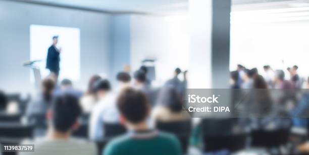 Blurred Defocused Audience In Conference Lecture Presentation Room Corporate Presentations In Conference Hall Seminar Speaker Giving Training To New Employees Blurred Hip Presenter Wearing Hat Stock Photo - Download Image Now