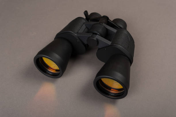 istock Black binoculars with orange lens on pastel background 1139841045