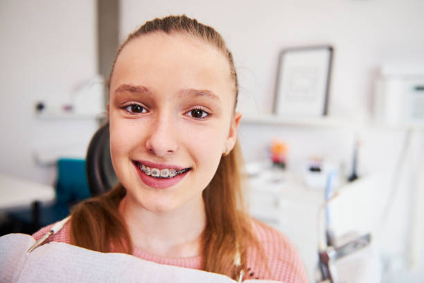 портрет улыбающейся девочки-подростка с брекетами - dentist teenager dental hygiene sitting стоковые фото и изображения