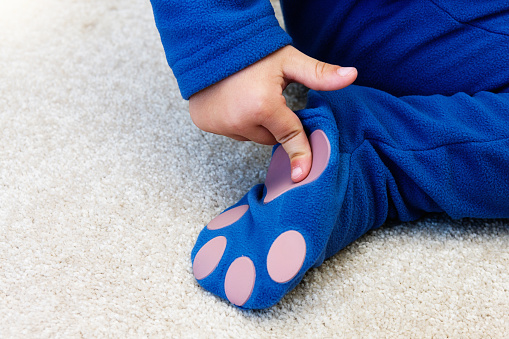 A child indicates the safety non-slip patches on the feet of his onesie-style sleepsuit.