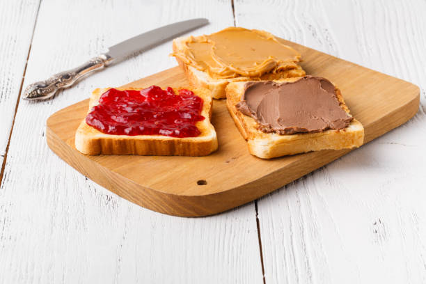 istock Toast with jam and peanut butter on rustic wooden cutting board - breakfast concept 1139846061