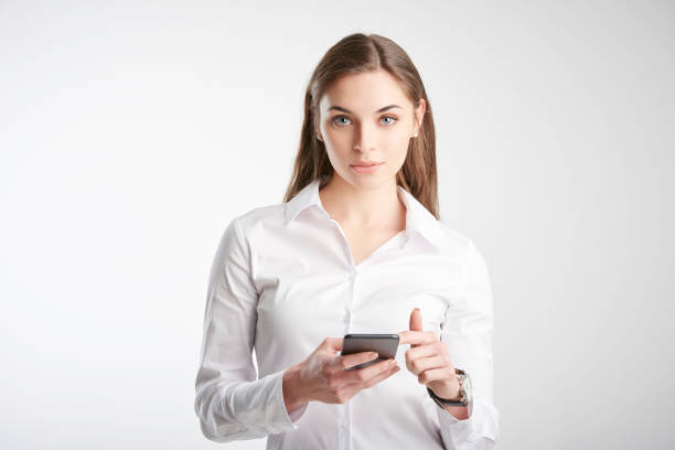 Young elegant businesswoman with papers dialing phone number to call one of colleagues for consultation