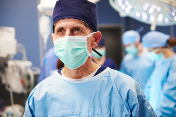 Portrait of senior surgeon ready for an operation Portrait of senior surgeon ready for an operation nurse smock stock pictures, royalty-free photos & images