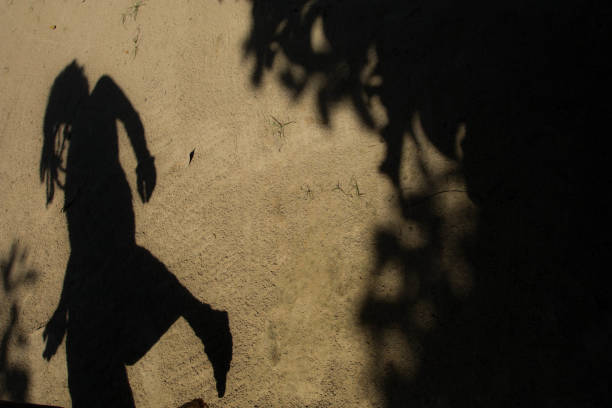 Shadows of people in various stance on soil background.