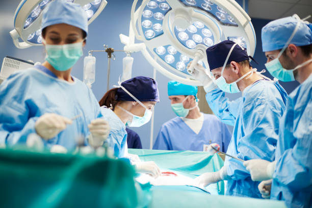 группа хирургов в операционной - operating room hospital medical equipment surgery стоковые фото и изображения