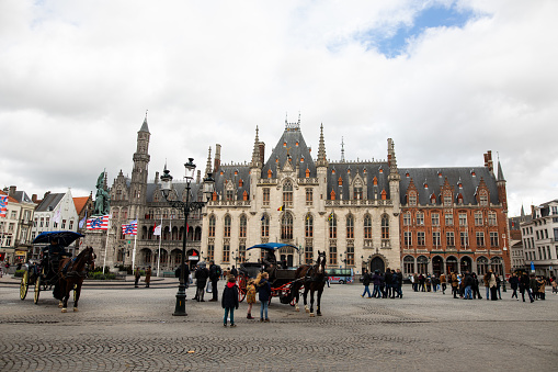 Belgium, Brugge: Horse carriages on Grote Markt square in medieval city Brugge at afternoonon cloudy day, Belgium