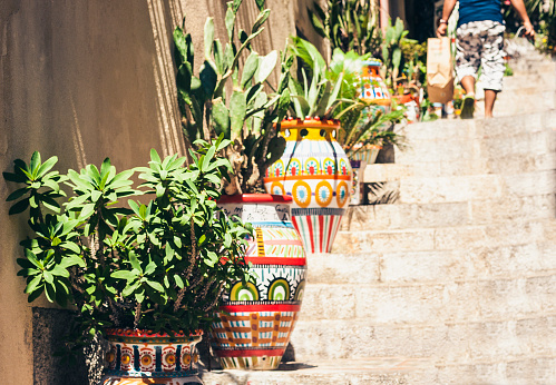 Plant in clay pot on the historic street of Taormina, Sicily, Italy, traditional architecture